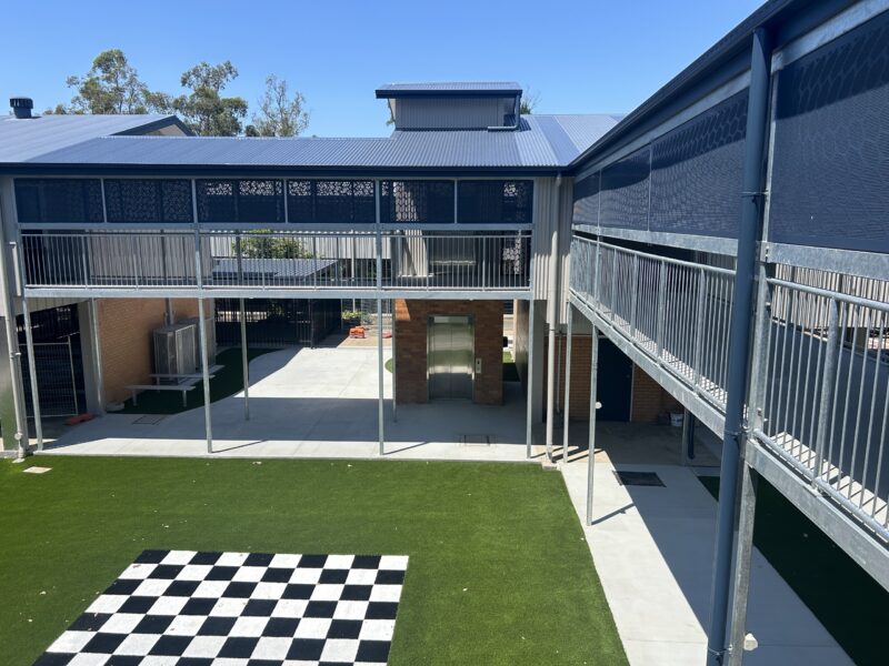 Elevated walkways and roof over the courtyard with chess-board turf in foreground.