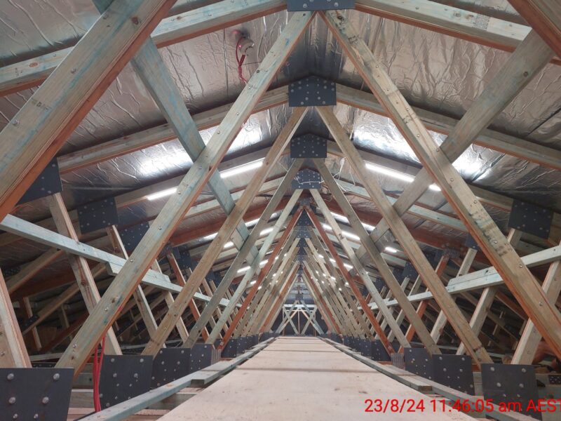 Long perspective through new timber roof trusses with steel plate connections in the roof space.