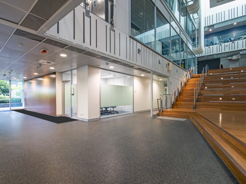 P Block atrium with timber tiered seating stair, glazed offices and terrazzo floor.