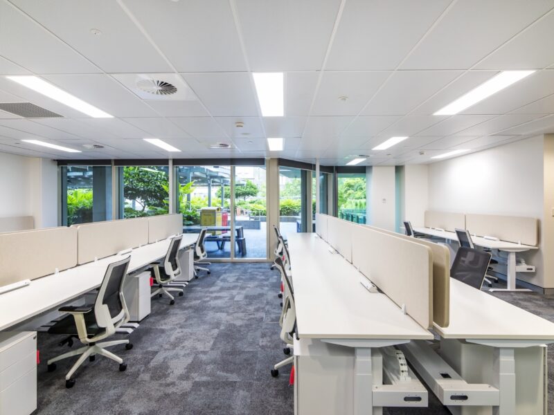Rows of workstations running to full-height glazing with garden views.