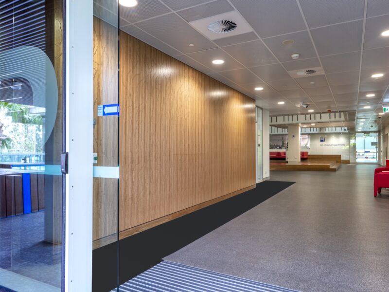 View through the glazed entry door down the timber-lined corridor to the atrium.