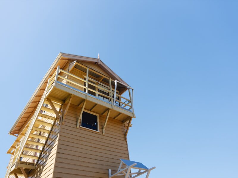 The three-storey restored signal cabin and its external timber stair against a clear sky.