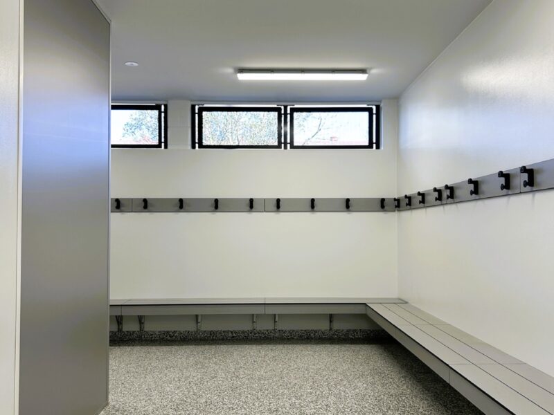 Changing room with timber bench seating, coat hooks and epoxy floor.